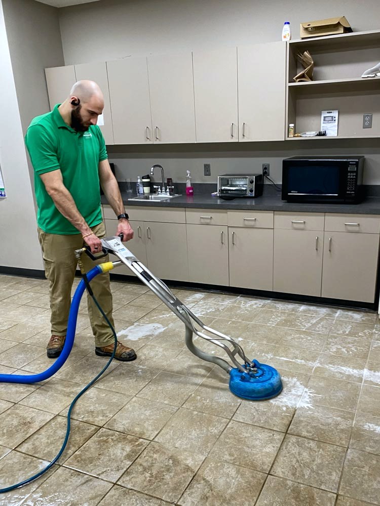 Technician deep-cleaning tile and grout with a rotary extraction tool