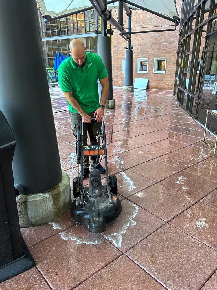 Technician machine-scrubbing an exterior tiled walkway