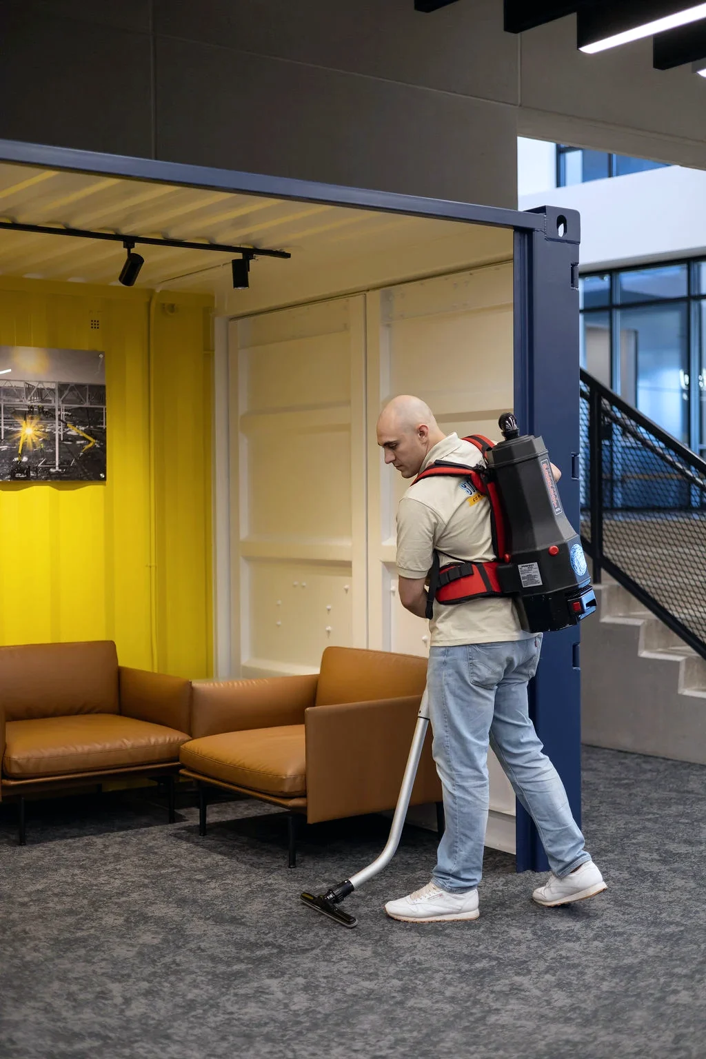 Technician vacuuming commercial carpet with a backpack vacuum